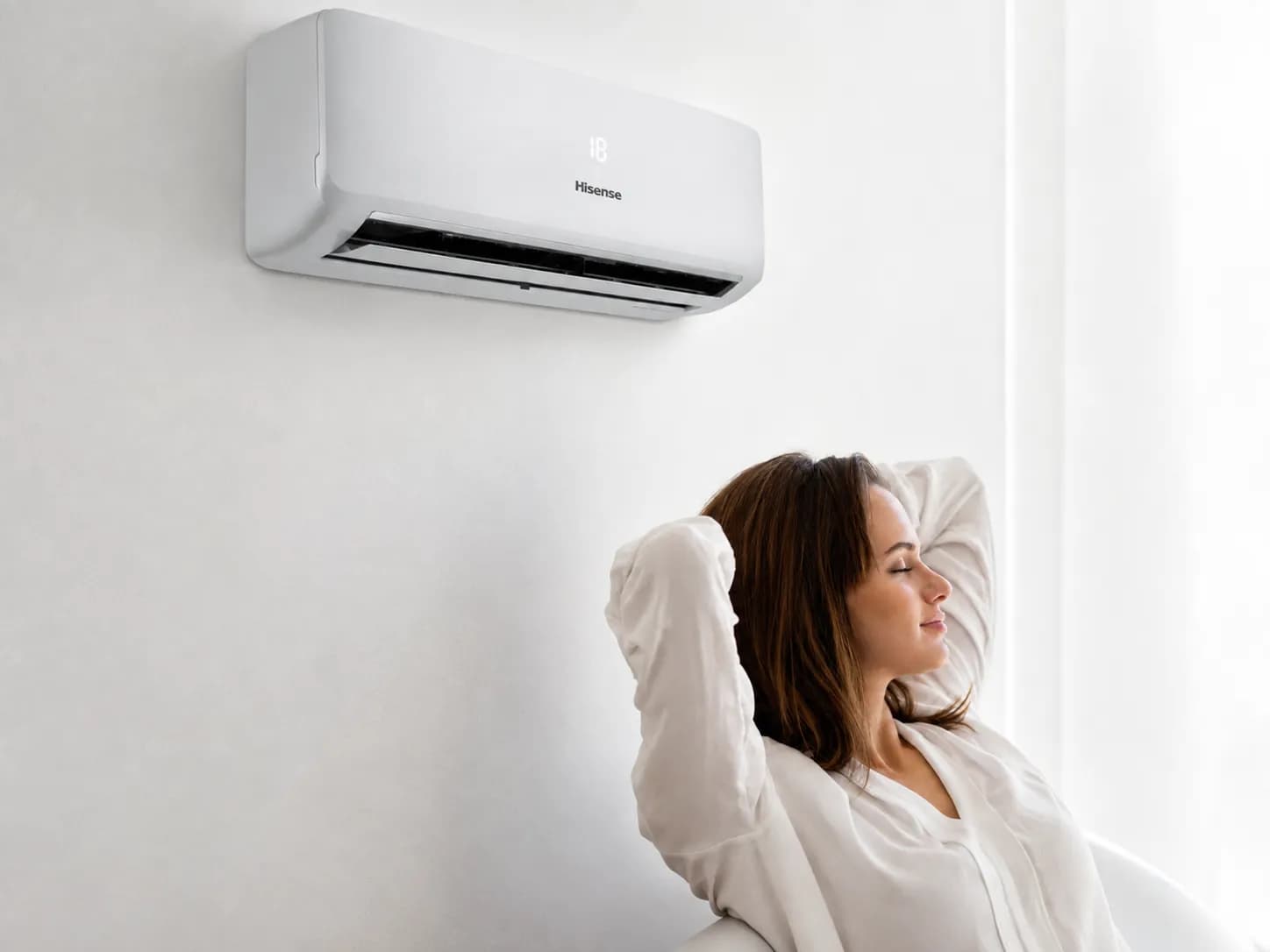 Woman relaxing in a bright lounge beside a Hisense wall-split air conditioner